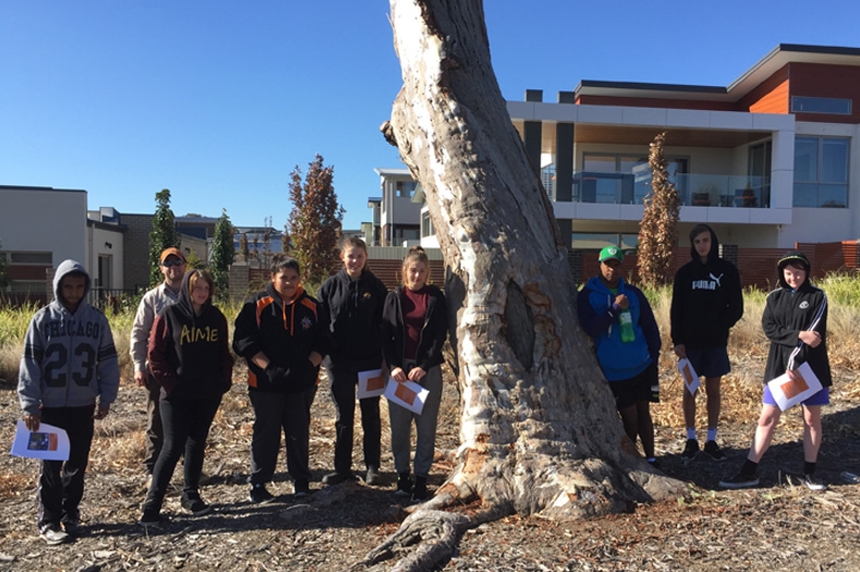 FLO graduates posing with their certificates alongside a local scar tree.