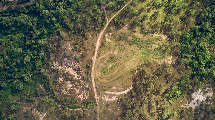 An aerial drone shot of a restored gully surrounded by luscious green grass, dark green trees and shrubbery.