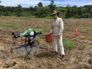 Greening Australia's Lisa O'Mara standing beside a drone being trialled for seed dispersal.