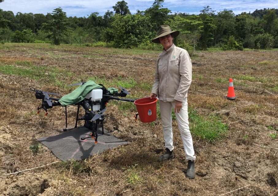 Greening Australia's Lisa O'Mara standing beside a drone being trialled for seed dispersal.