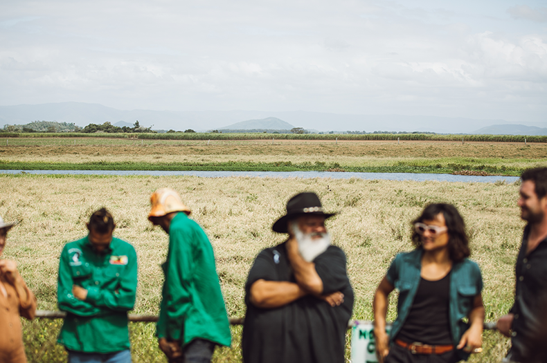 Blurred people in the foreground with a light green and blue backdrop of wetlands at Mungalla Station.