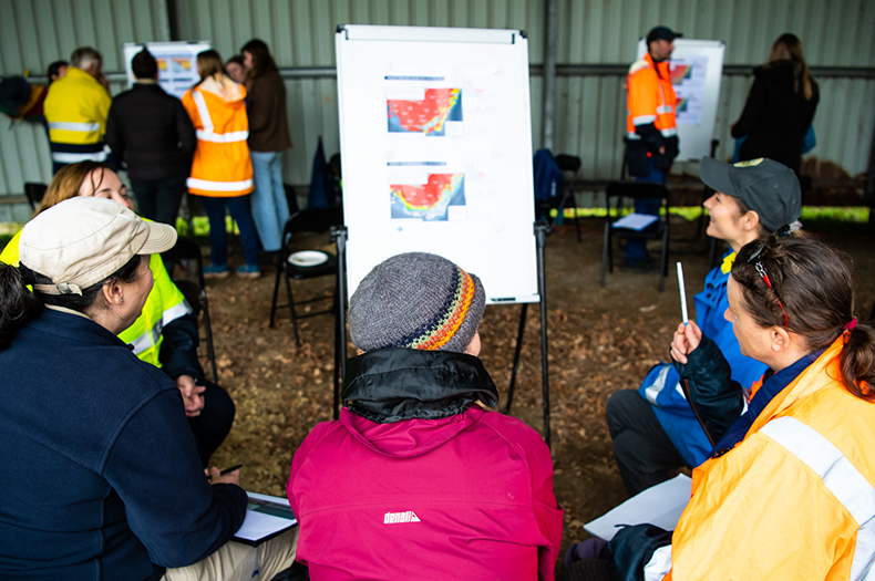 A small group of people are discussing two maps showing predicted future changes in Victoria's climate.